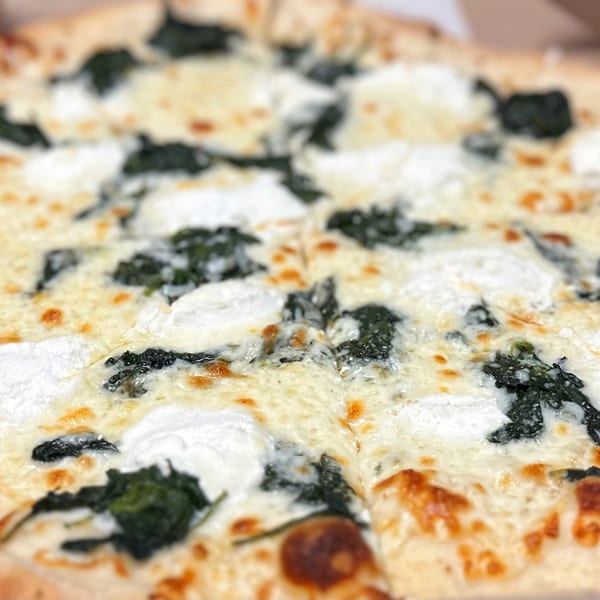 Primo Brothers Pizza's white pizza with spinach and ricotta cheese, sliced and ready to eat.
