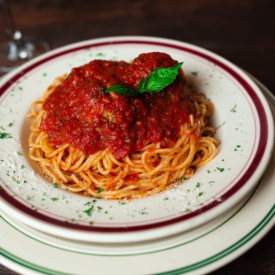 Primo Brothers Pizza's spaghetti and meatballs with red sauce, basil, and Parmesan cheese.