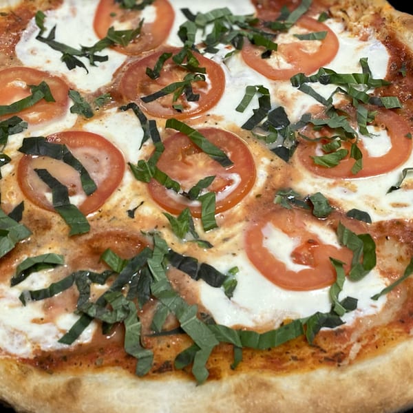 Primo Brothers Pizza's Margherita pizza with fresh mozzarella, sliced tomatoes, and basil.