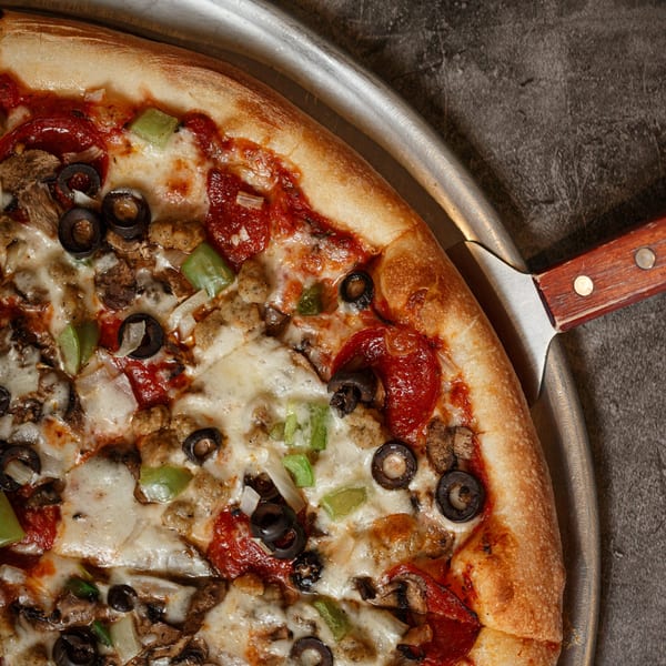 Close-up of a Primo Brothers Pizza with pepperoni, sausage, olives, mushrooms, and green peppers.