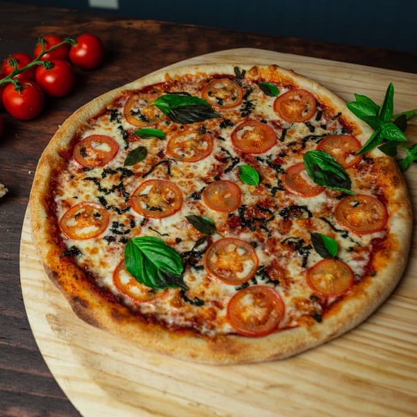 Primo Brothers Pizza's Margherita pizza with fresh tomatoes, basil, and balsamic glaze on a wooden peel.