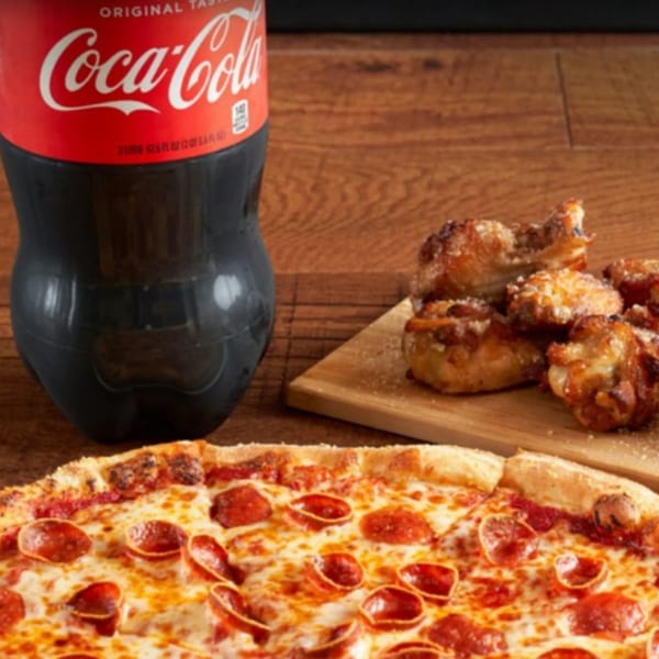 Primo Brothers Pizza pepperoni pizza, chicken wings, and a Coca-Cola bottle on a wooden table.